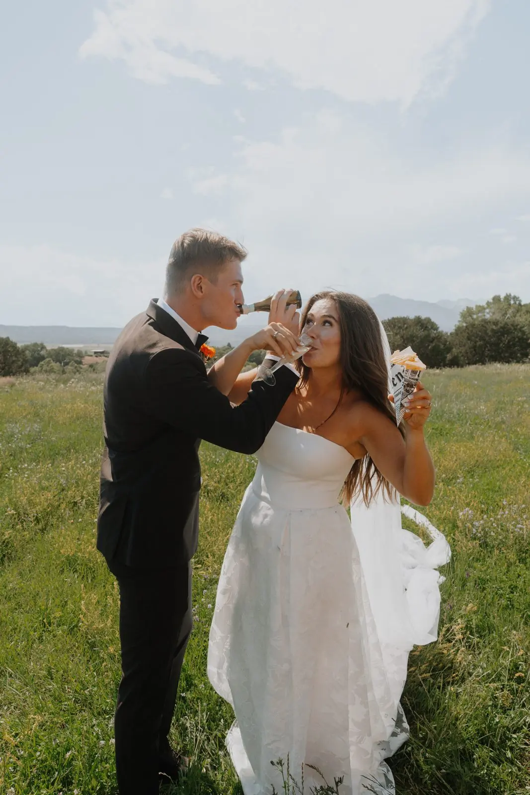 Brady and Mary on their wedding day in a grassy field, sipping coffee
