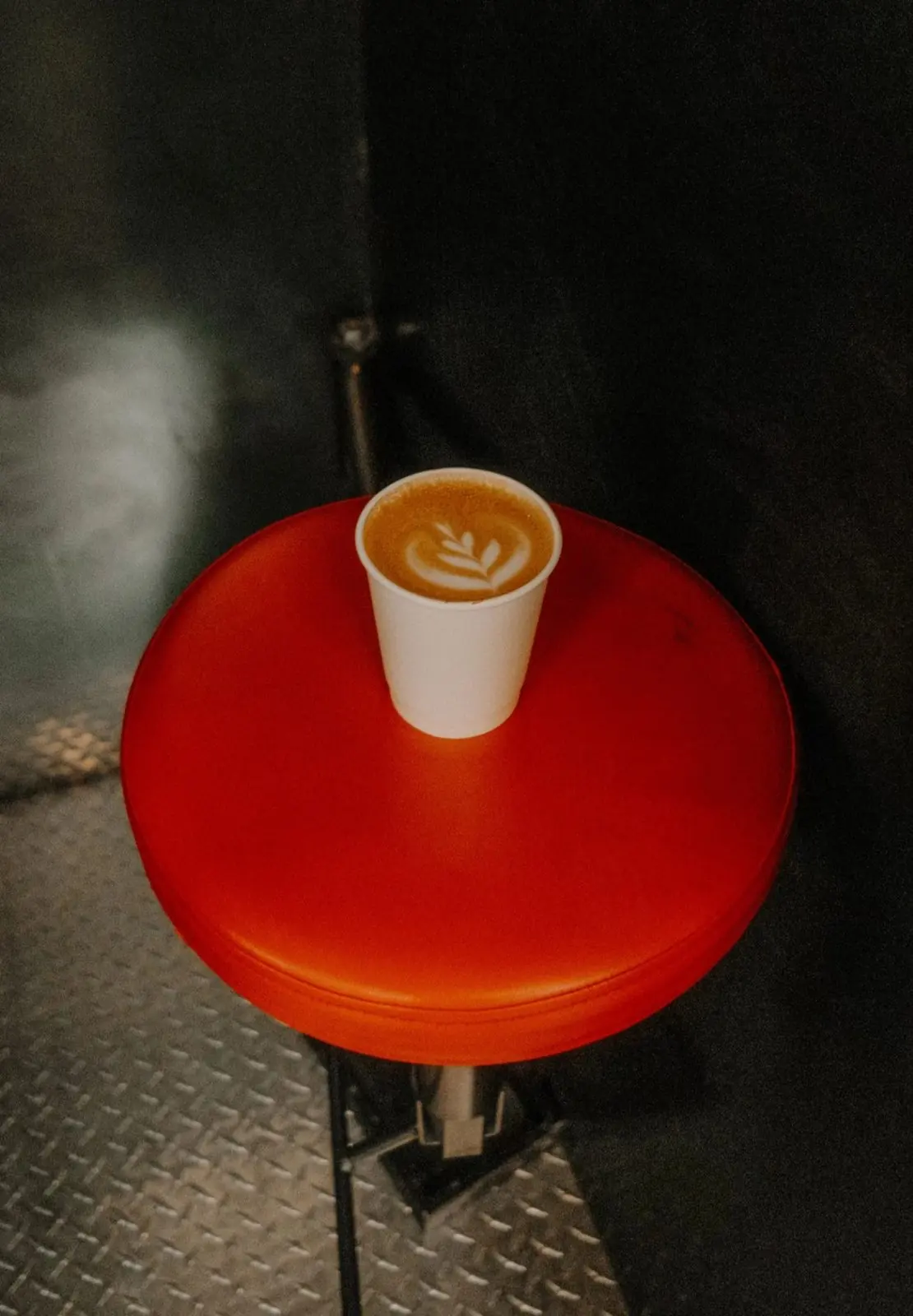 A latte with rosetta art on a red stool