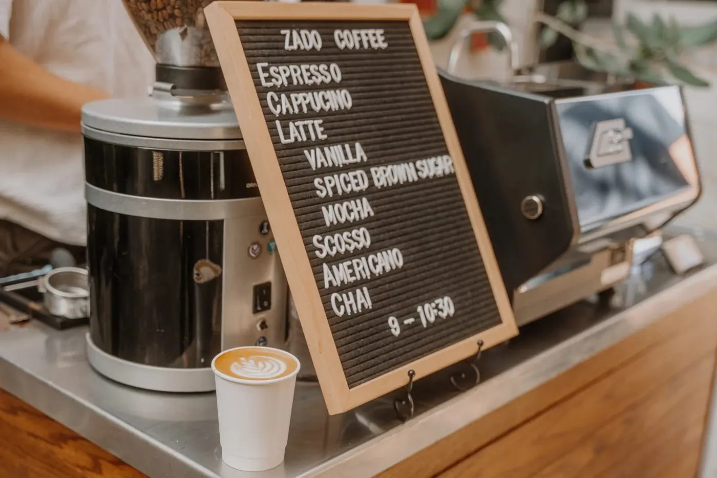 The Zado letterboard menu beside the grinder, with a latte in front
