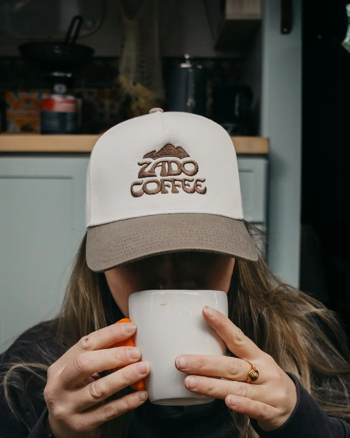 Someone wearing the Zado Two-Tone Hat while sipping from a mug