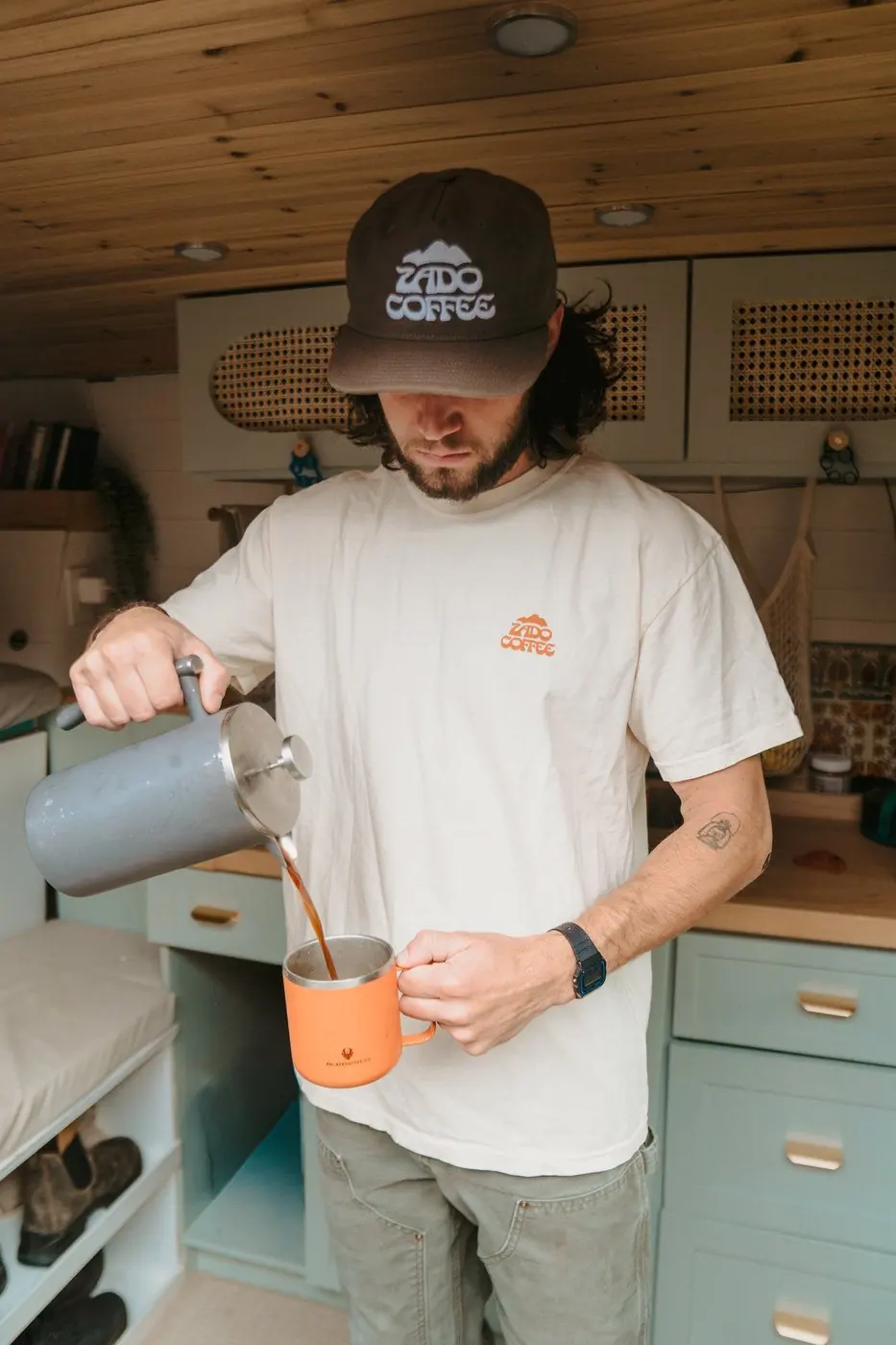 A barista pouring coffee while wearing the Zado Goldminer Tee