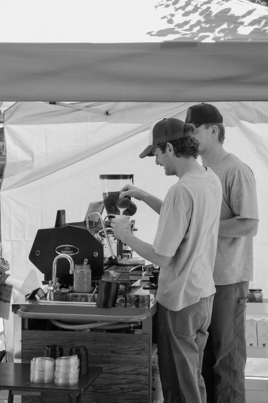 Two Zado baristas working under a tent, in black and white