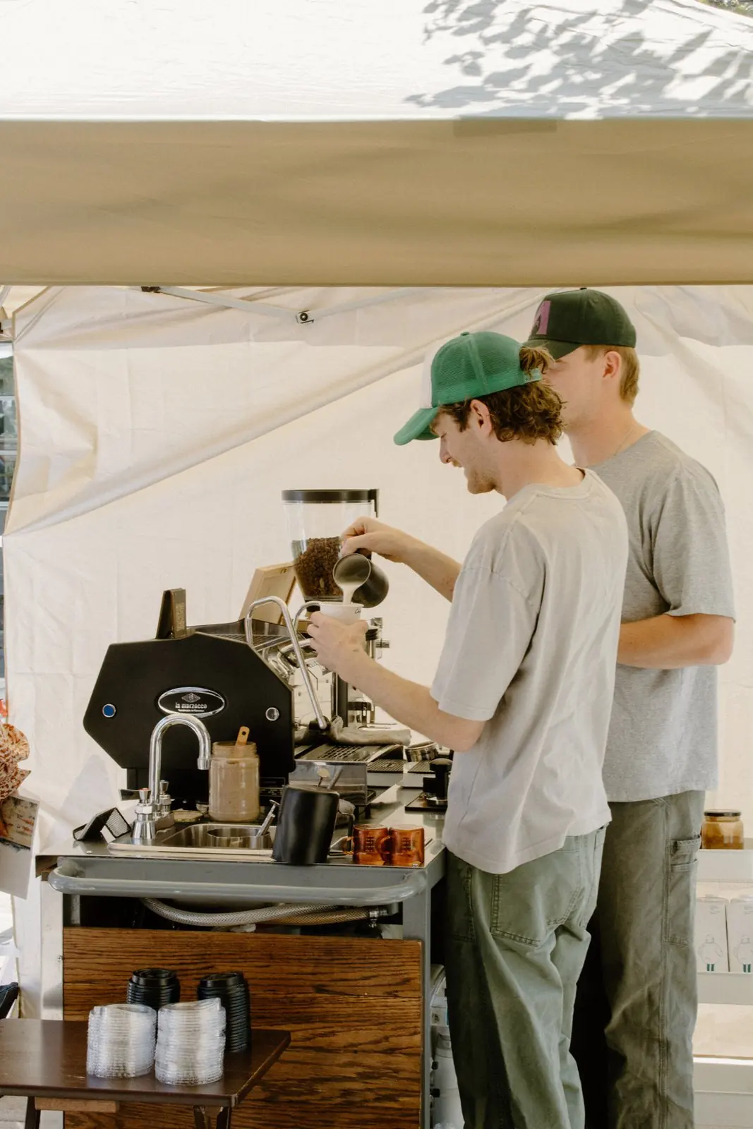 Two Zado baristas pouring drinks under a tent
