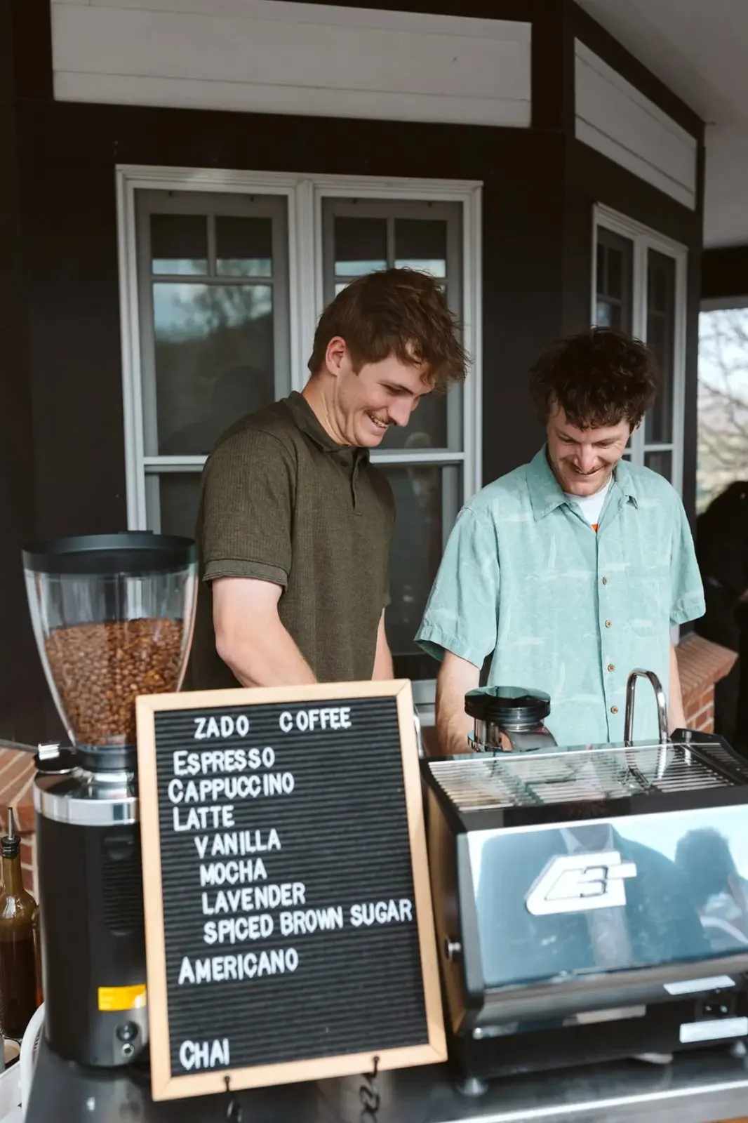 Two Zado baristas smiling behind the espresso machine